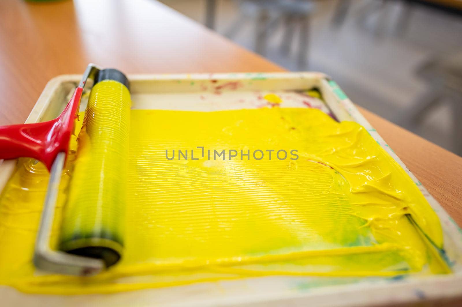 Roll of yellow paint prepared in a tray in a worker's hand before painting