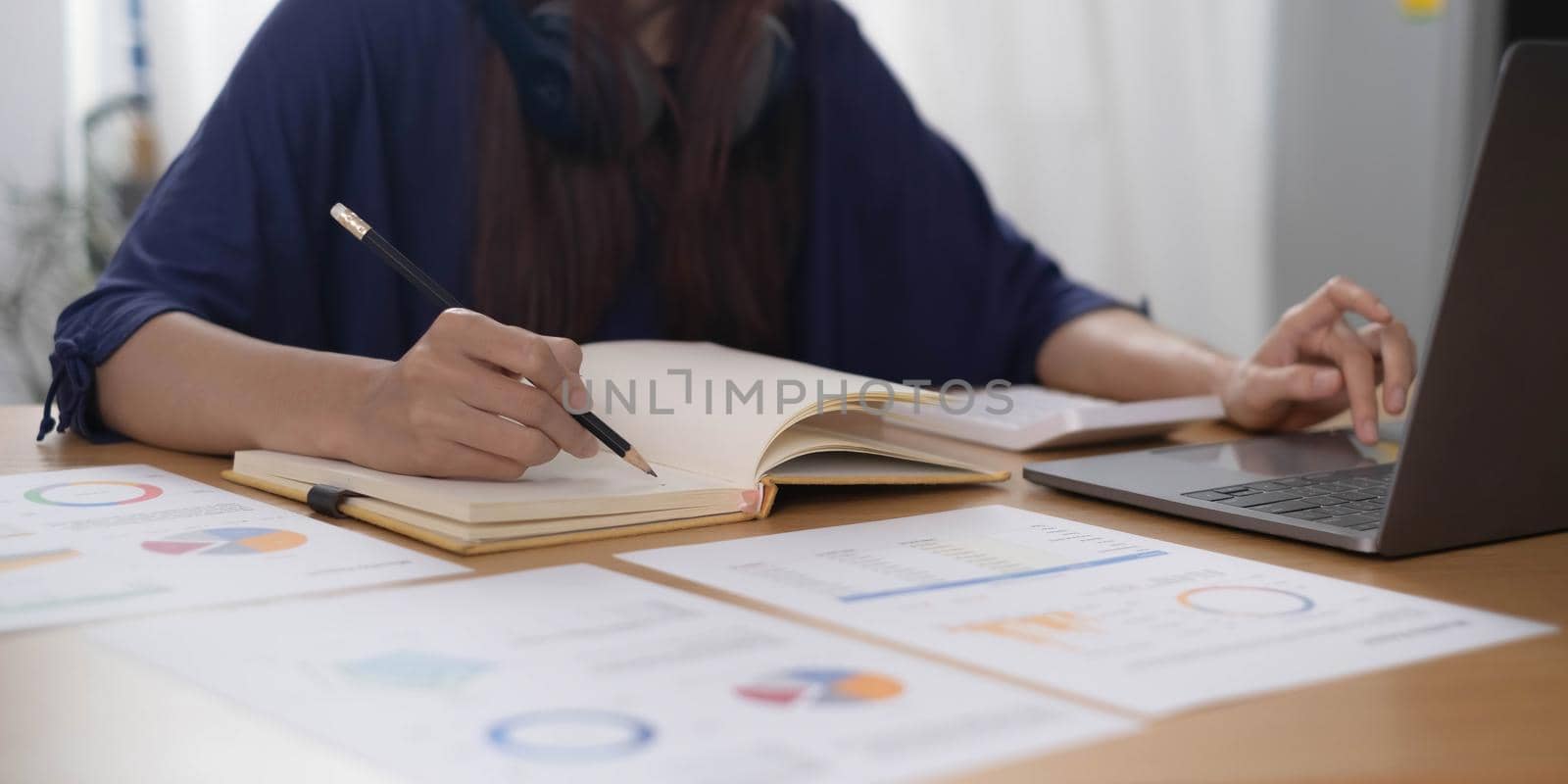 Close up of woman or accountant hand holding pencil working on calculator to calculate financial data report, accountancy document and laptop computer at office, business concept.