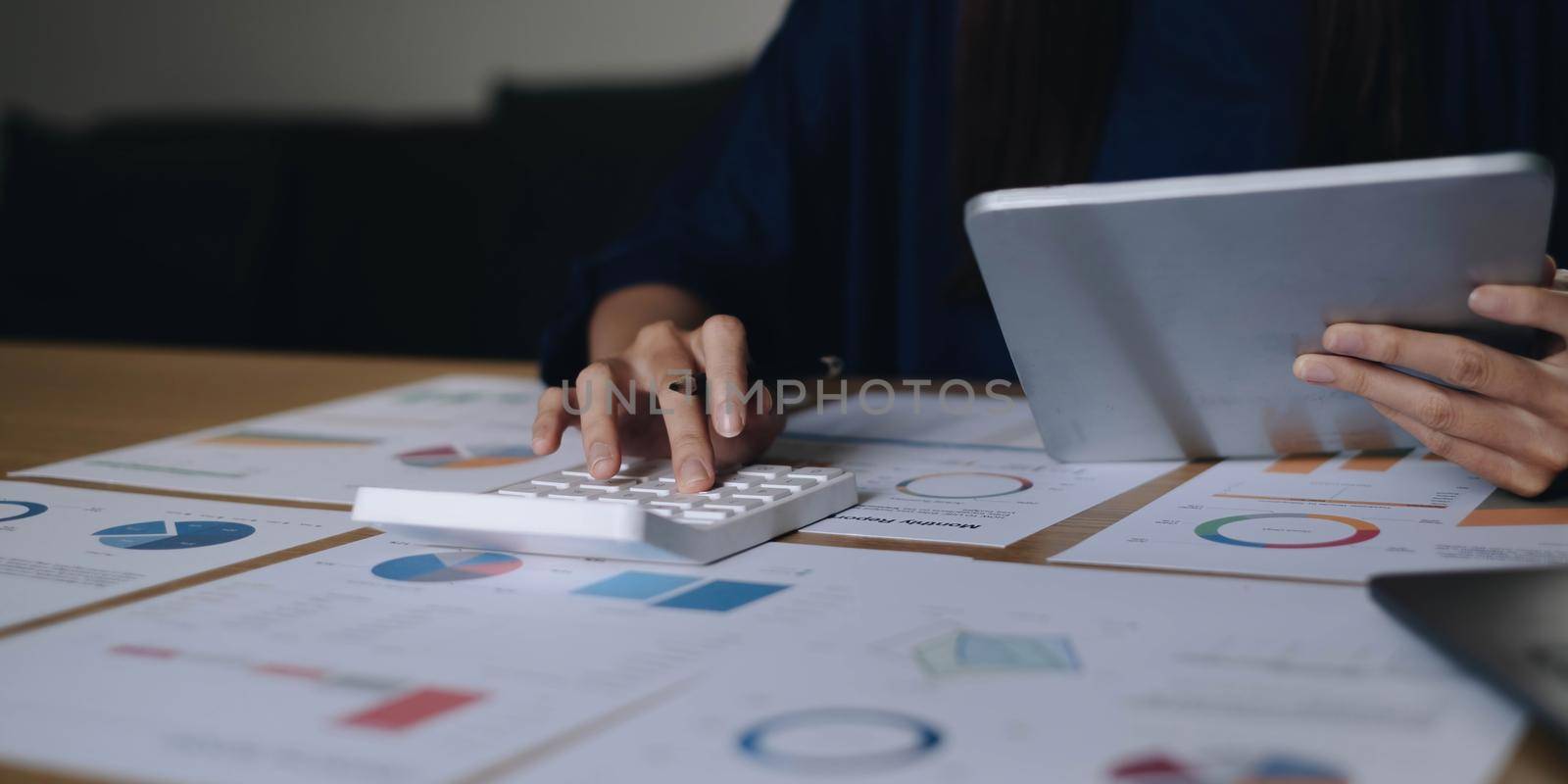 Close up Businesswoman using calculator and laptop for calaulating finance, tax, accounting, statistics and analytic research concept by wichayada