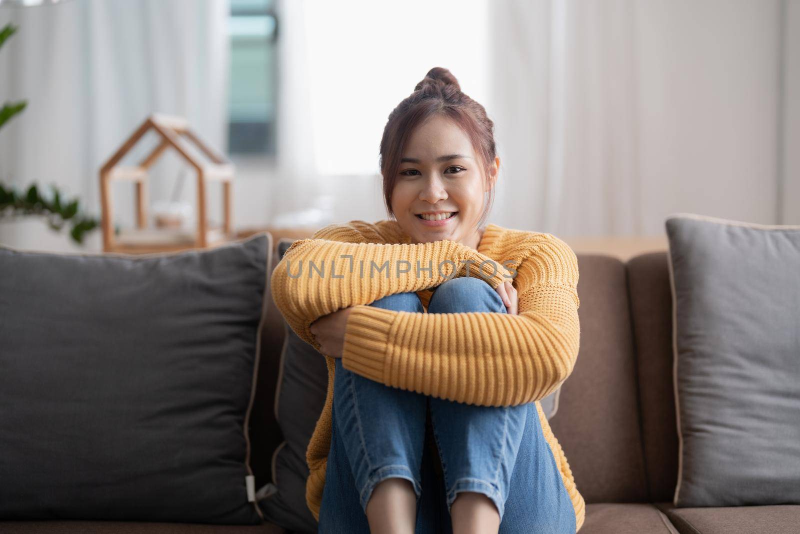 Calm asian woman relaxing on comfortable sofa in living room, portrait female looking on camera at cozy home.