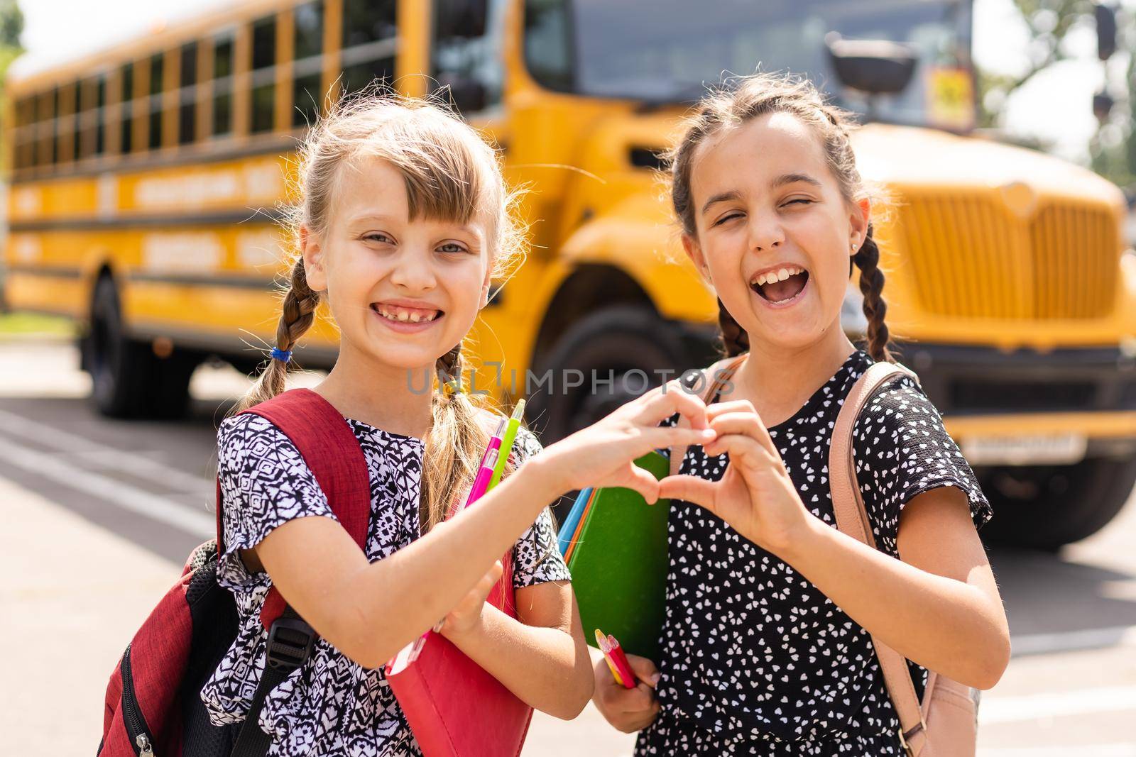 Education: Smiling Student Friends Ready For School next to school bus.
