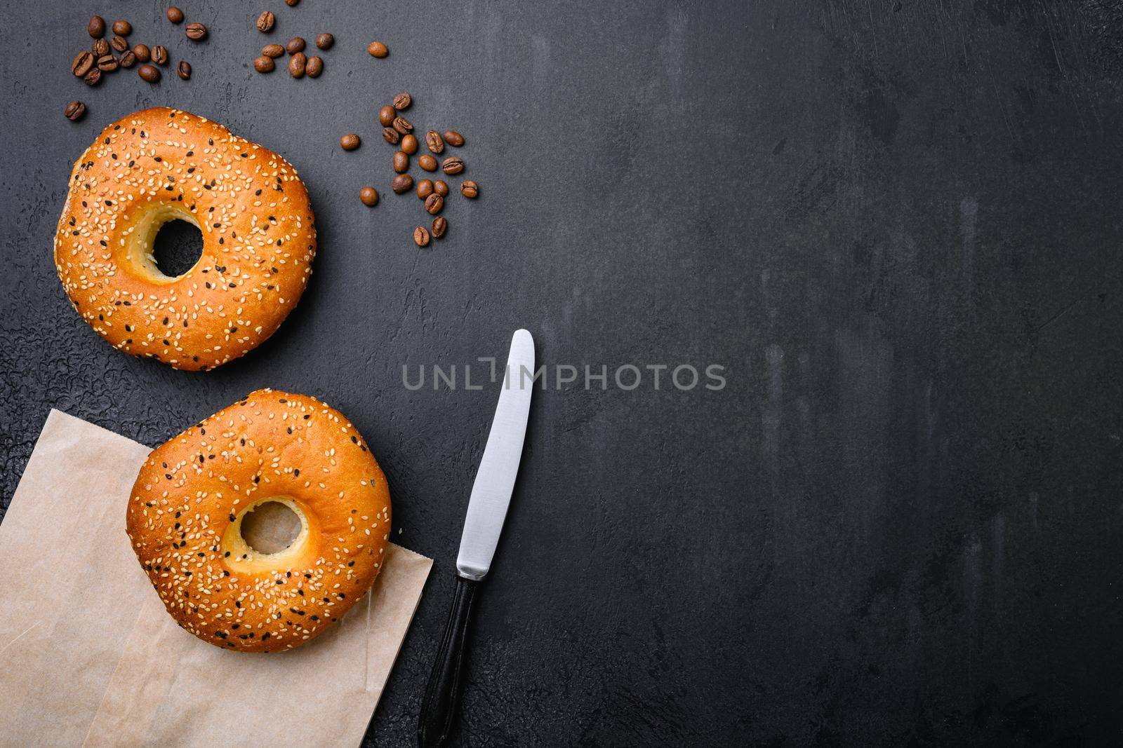 Fresh Bagels with Sesame, on black dark stone table background, top view flat lay, with copy space for text