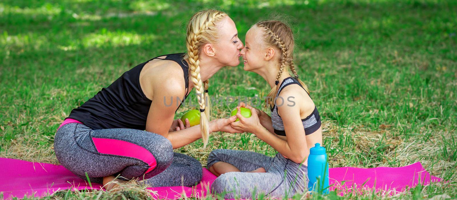 Mother kissing her daughter in the park by okskukuruza