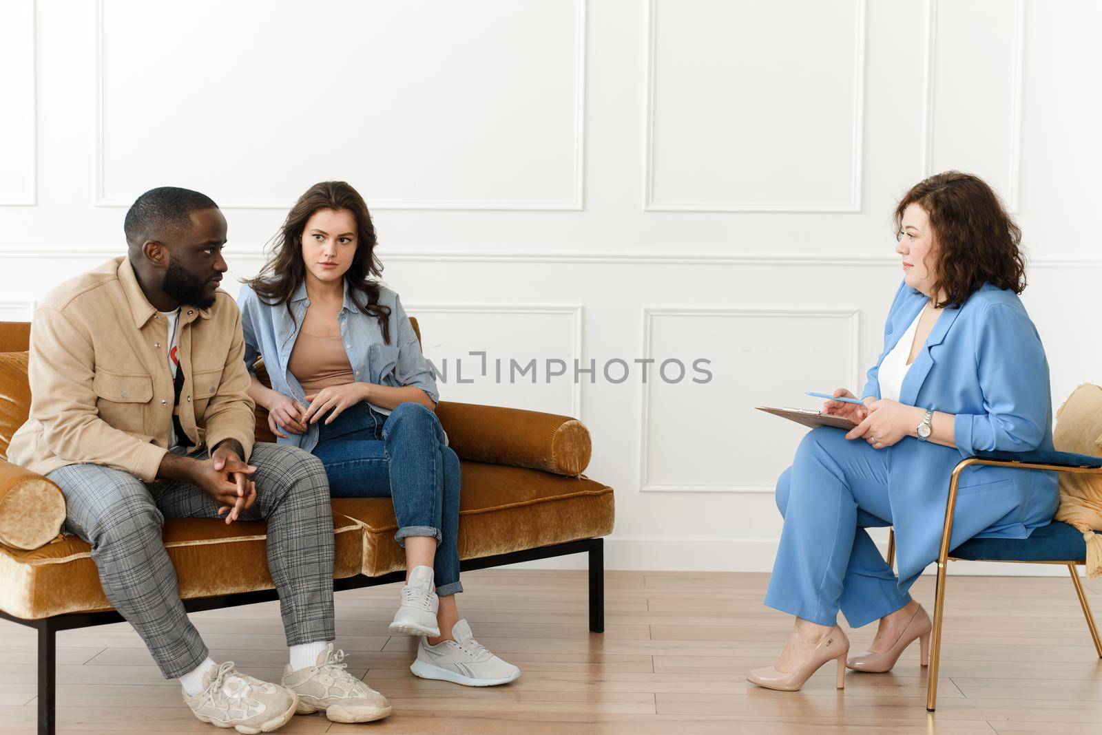 Stressed unhappy millennial Caucasian and African American couple have relationship problems. Diverse couple fighting while visiting professional psychologist for help, breakup prevention concept