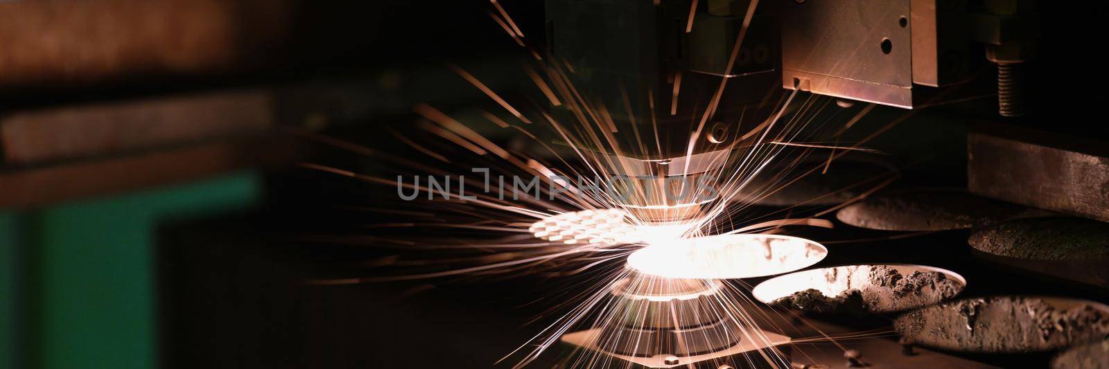 Close-up of sparks fly out machine head for metal processing laser metal. Cutting machine cut metal plate. Manufacturing for automotive production concept