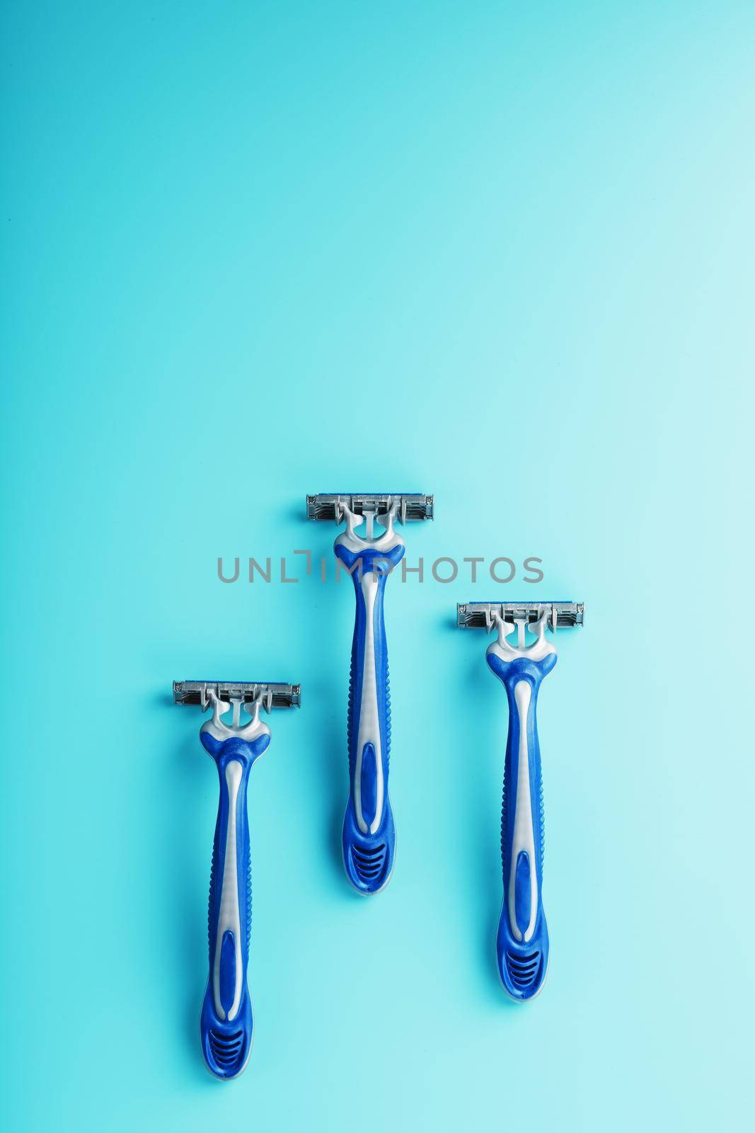 Blue shaving machine with sharp blades on the background of ice cubes close-up. The concept of cleanliness and frosty freshness