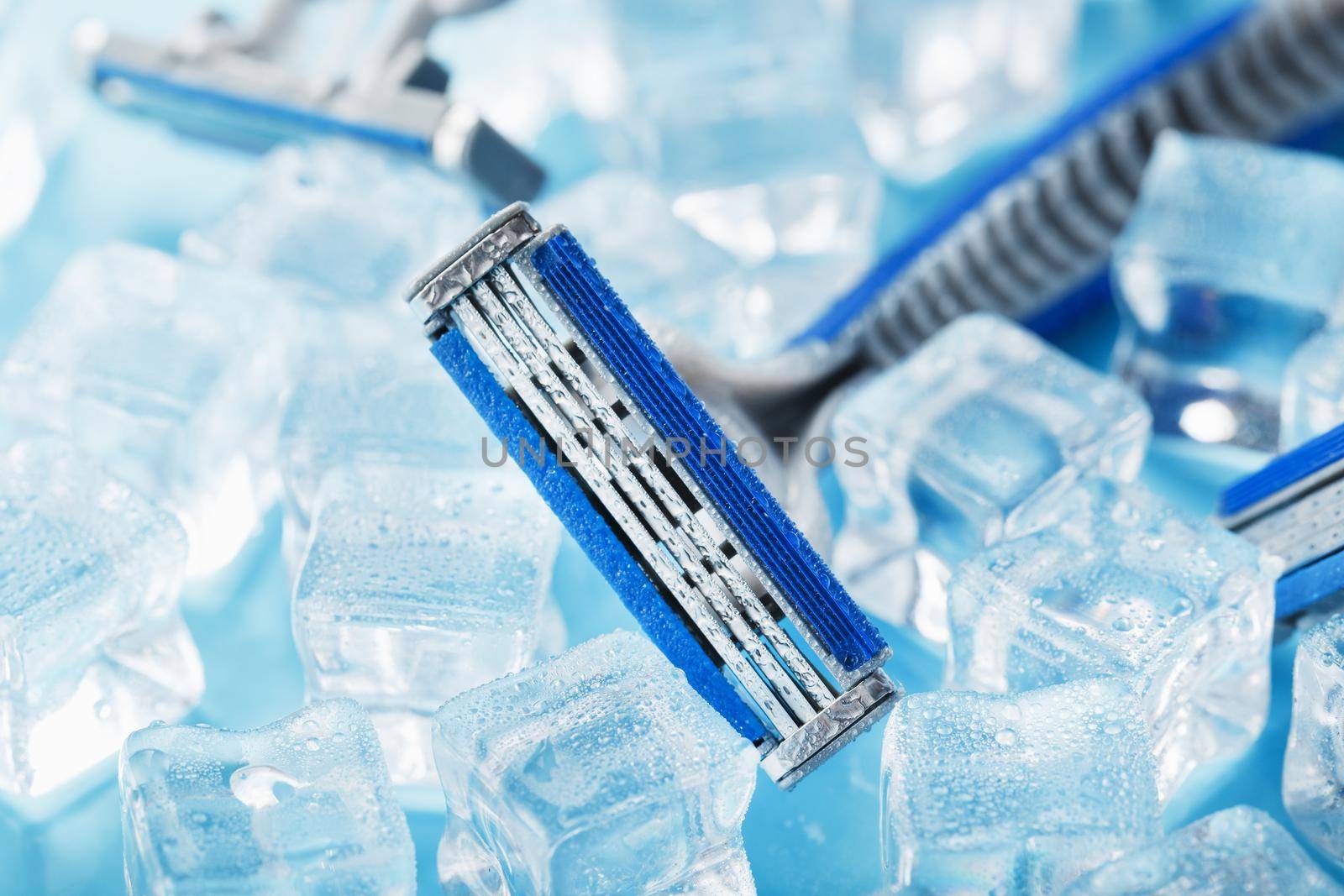 Shaving machine on a blue background with ice cubes. The concept of cleanliness and frosty freshness