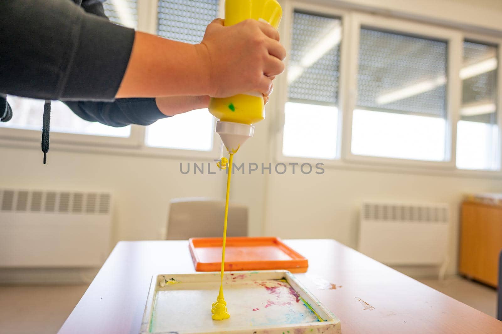 Worker squeezing yellow paint from tube into tray to prepare it for painting