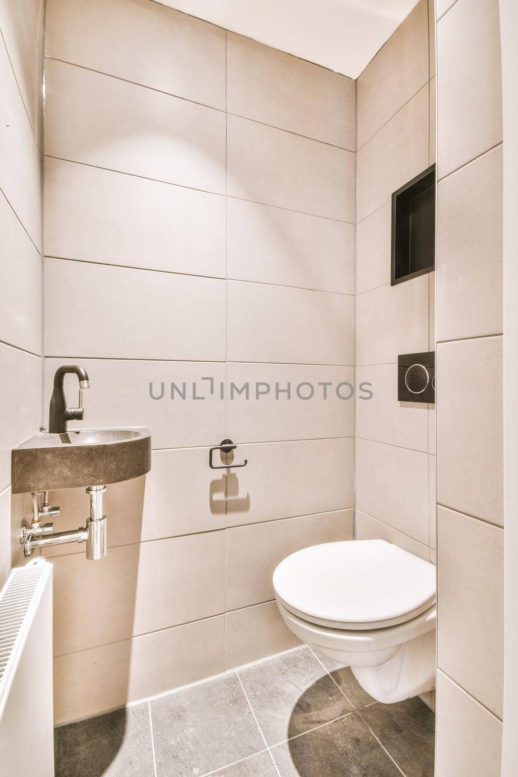 Modern flush toilet and ceramic sink installed on white tiled walls near mirror and towel in small restroom at home