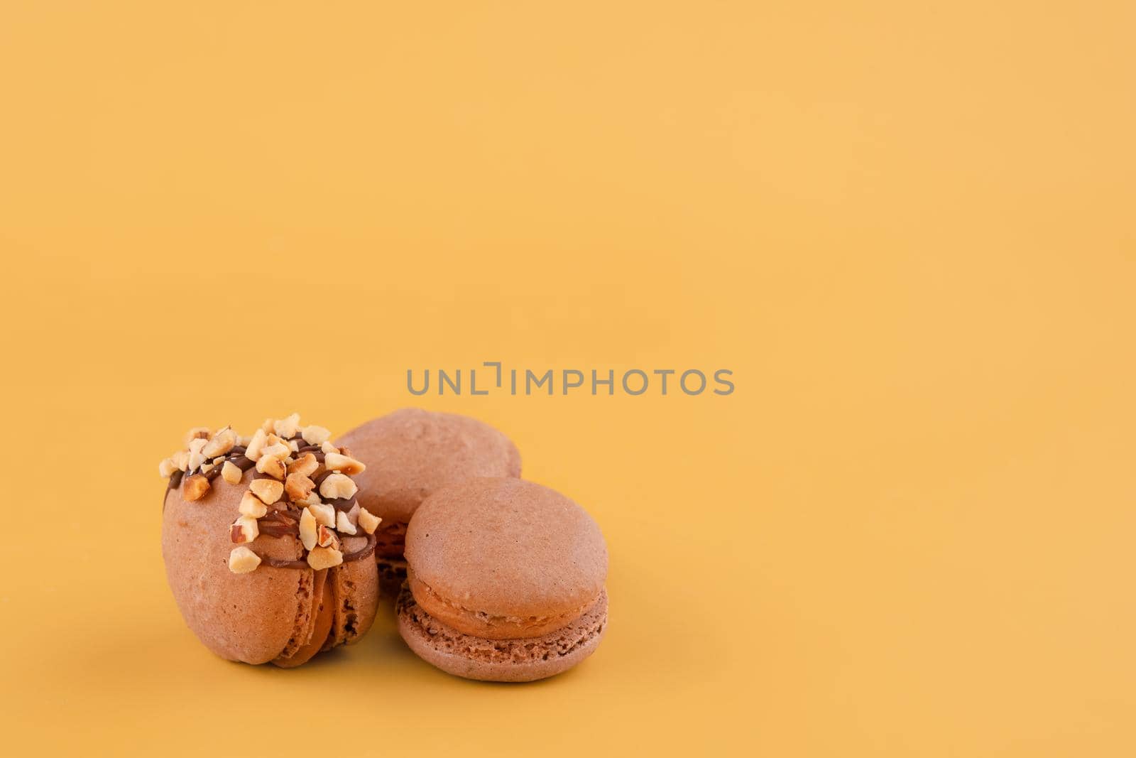 Several macaroons of various flavours on yellow background. Space for text