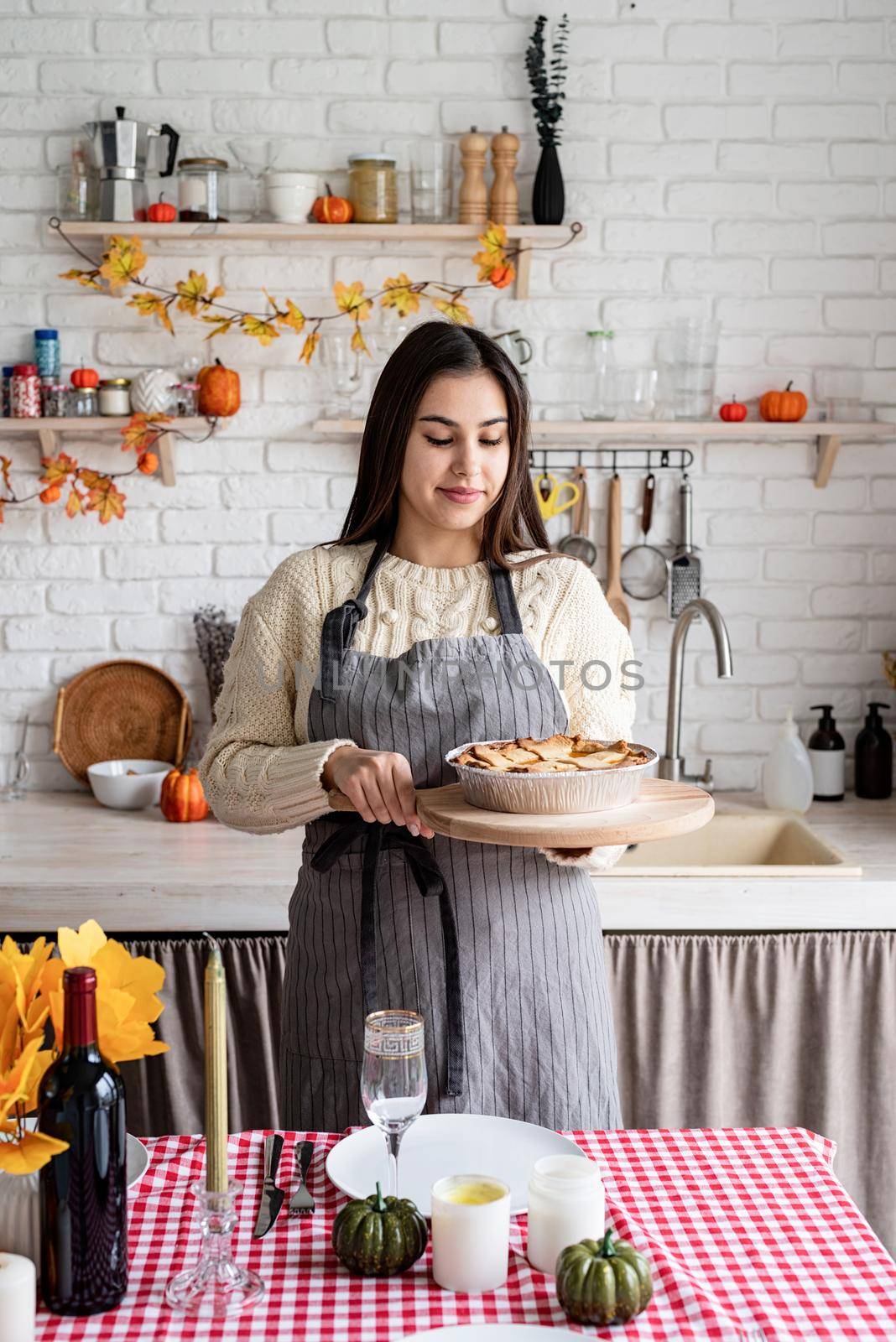 Portrait of a woman preparing pumpkin pie for thanksgiving dinner at home kitchen by Desperada