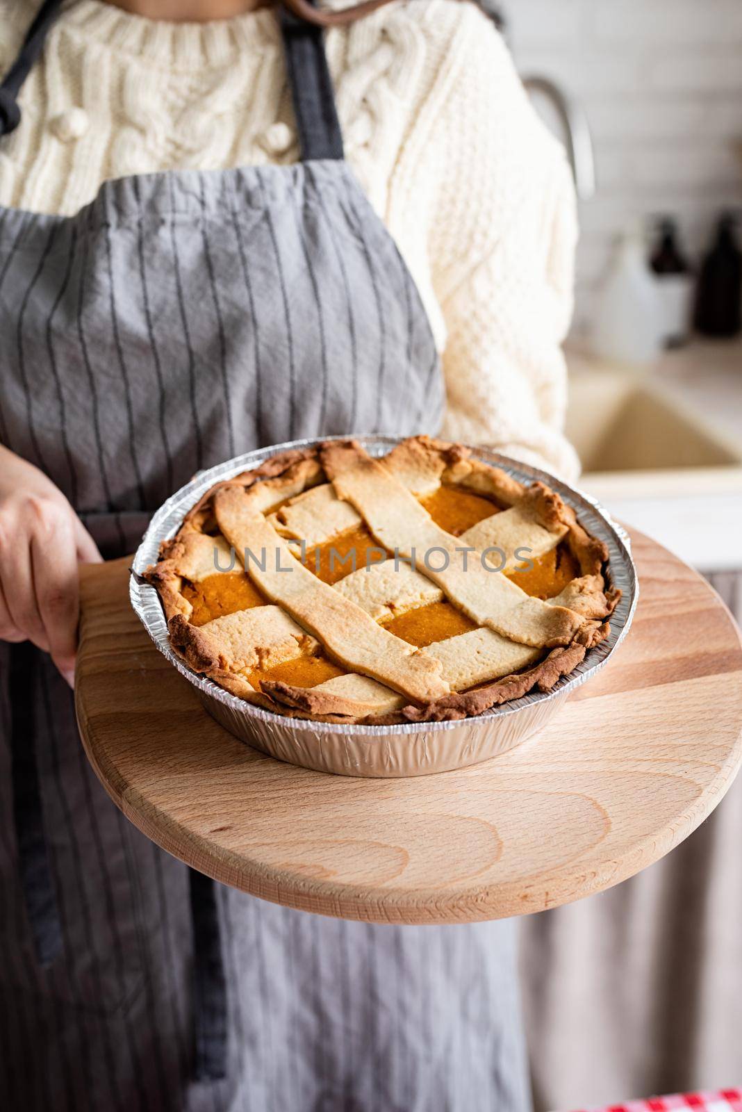 woman preparing pumpkin pie for thanksgiving dinner at home kitchen by Desperada