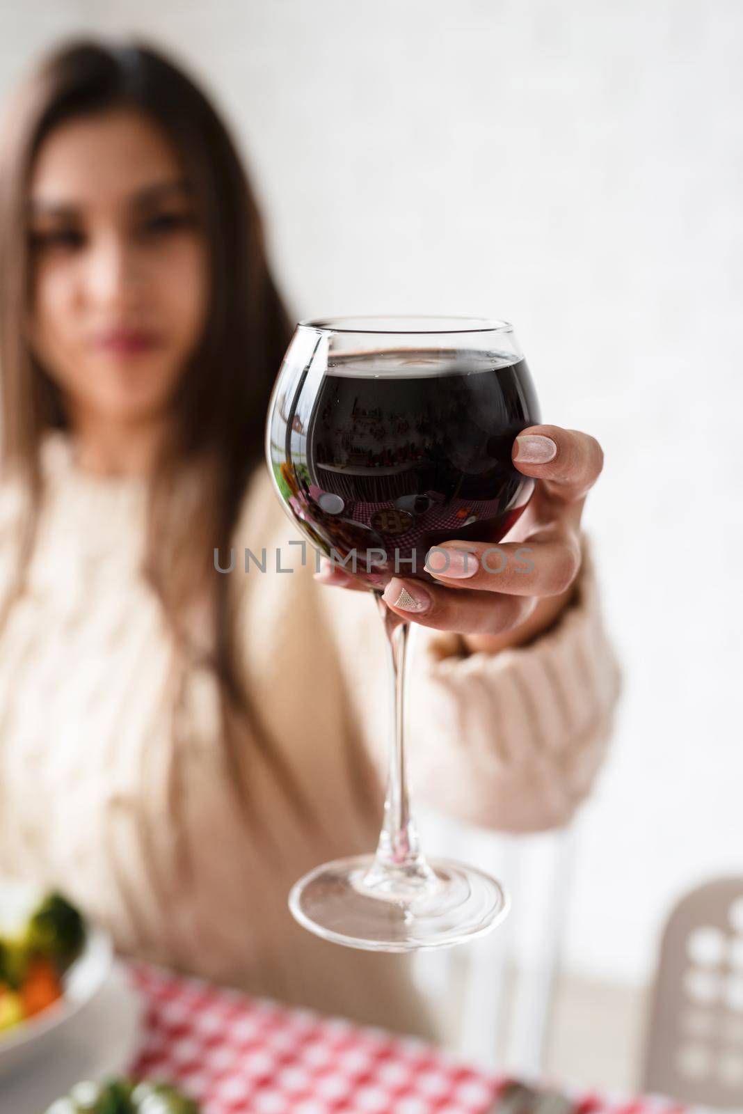 woman having thanksgiving dinner at home kitchen celebrating holiday, holding wine glass by Desperada