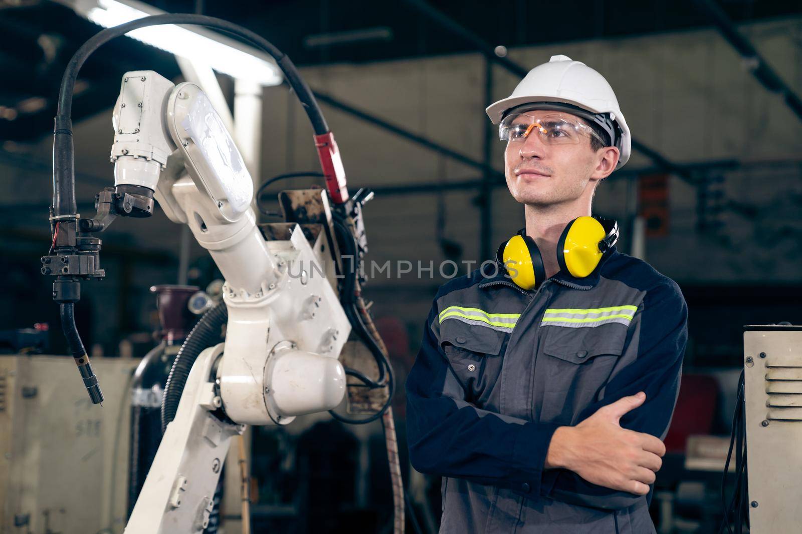 Young factory worker working with adept robotic arm in a workshop . Industry robot programming software for automated manufacturing technology .