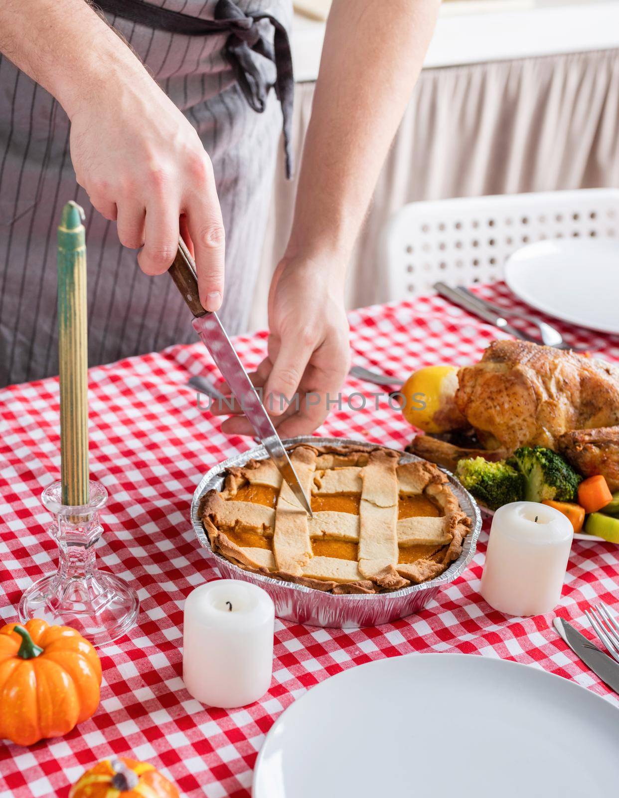 Happy Thanksgiving Day. Autumn feast. Woman celebrating holiday cooking traditional dinner at kitchen with turkey, vegetables and pumpkin pie, cutting pie