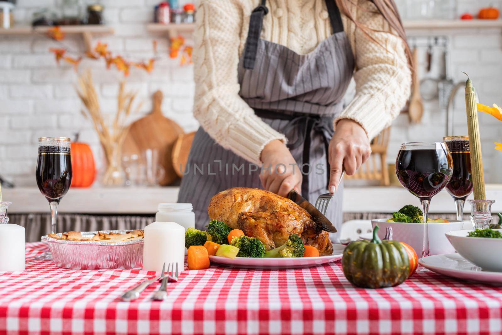 Happy Thanksgiving Day. Autumn feast. Woman celebrating holiday cooking traditional dinner at kitchen with turkey, vegetables and pumpkin pie, cutting