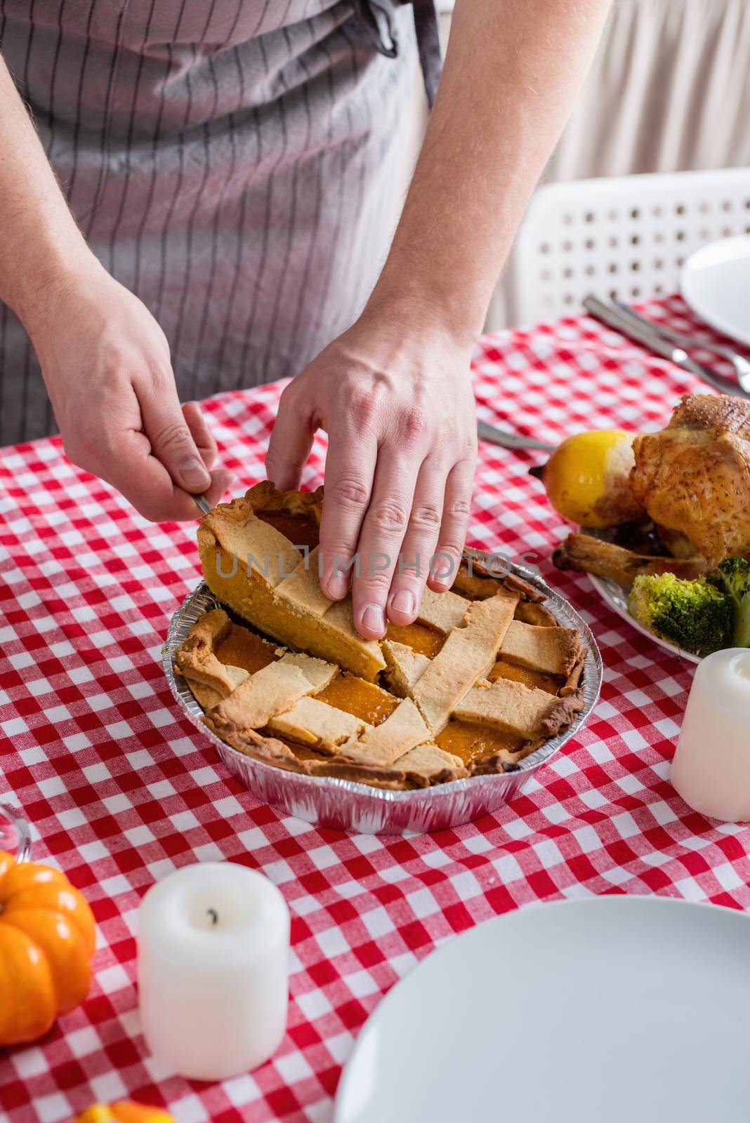 Happy Thanksgiving Day. Autumn feast. Woman celebrating holiday cooking traditional dinner at kitchen with turkey, vegetables and pumpkin pie, cutting pie