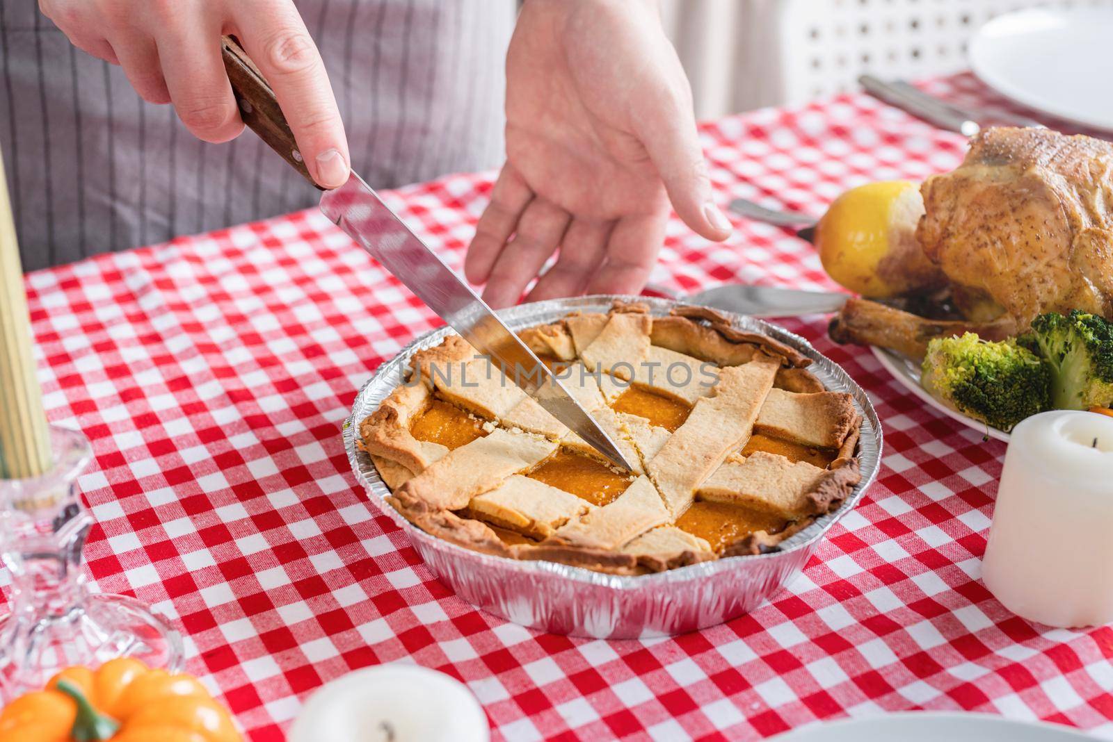 Happy Thanksgiving Day. Autumn feast. Woman celebrating holiday cooking traditional dinner at kitchen with turkey, vegetables and pumpkin pie, cutting pie