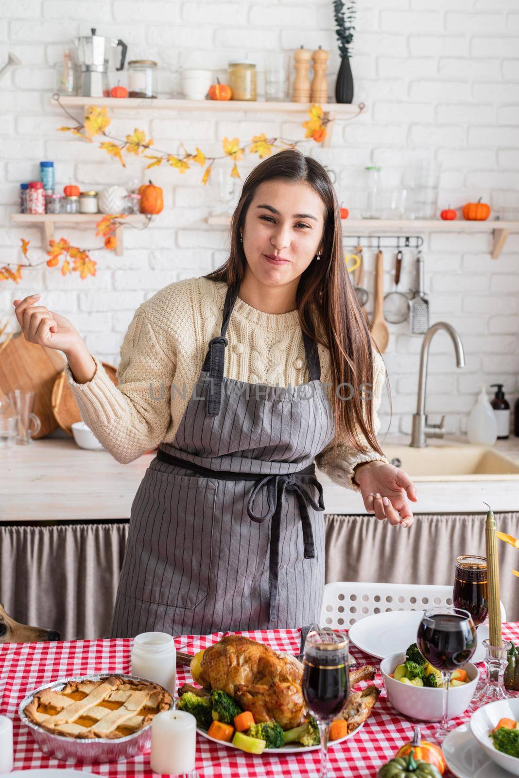 Happy Thanksgiving Day. Autumn feast. Woman celebrating holiday cooking traditional dinner at kitchen with turkey, vegetables and pumpkin pie, cutting pie