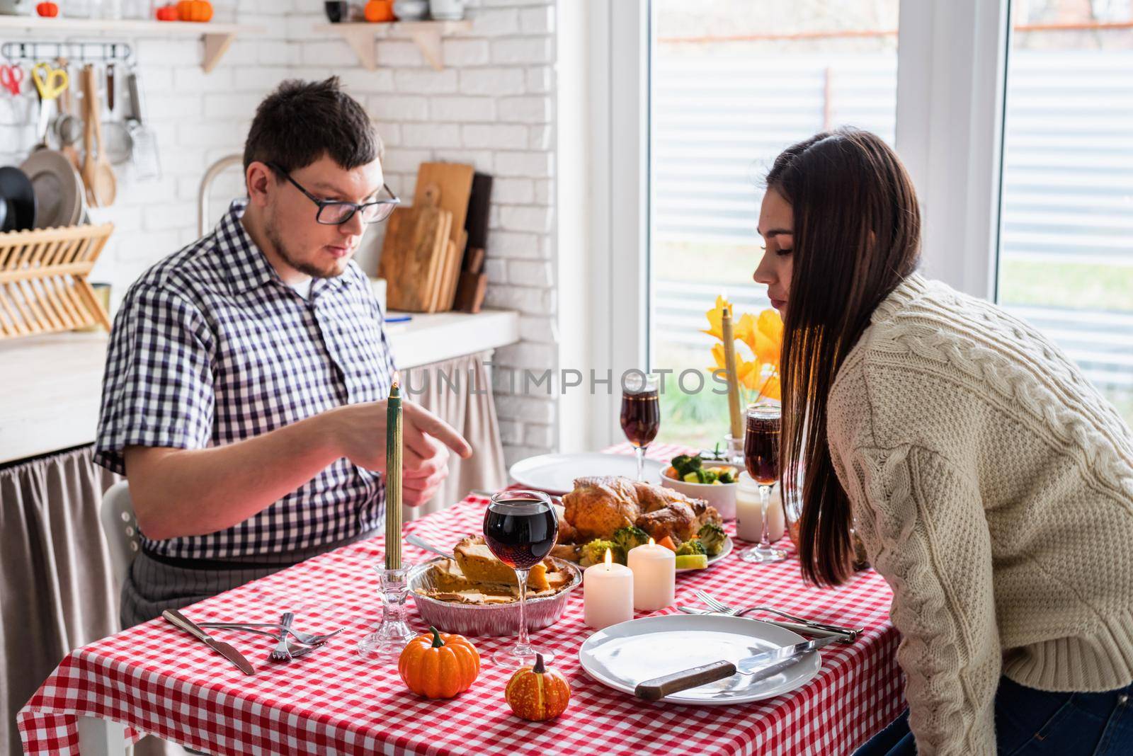 Happy Thanksgiving Day. Autumn feast. Woman and man celebrating holiday eating traditional dinner at kitchen with turkey, vegetables and pumpkin pie