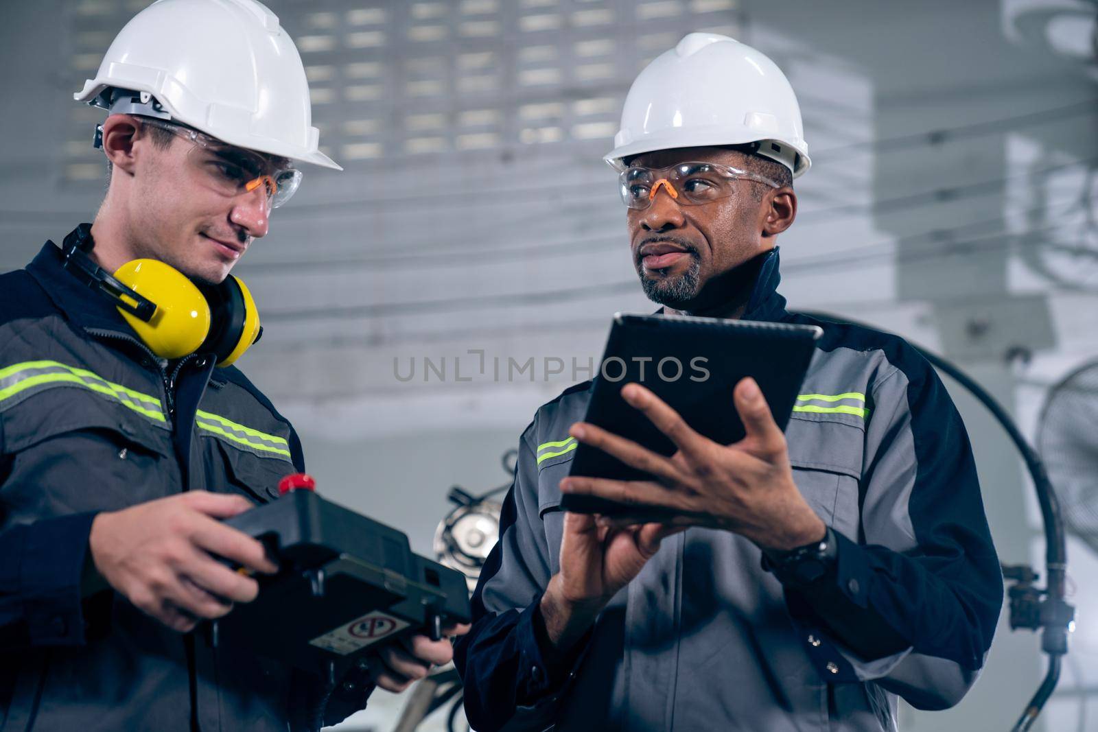 Group of factory job workers using adept machine equipment in a workshop . Industry manufacturing and engineering technology concept .