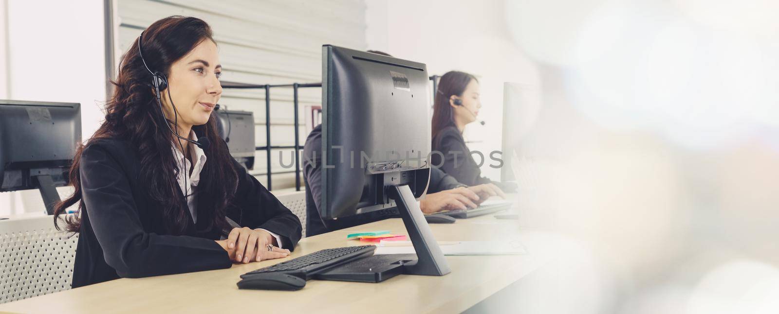 Business people wearing headset working in office to support remote customer or colleague. Call center, telemarketing, customer support agent provide service in broaden view .