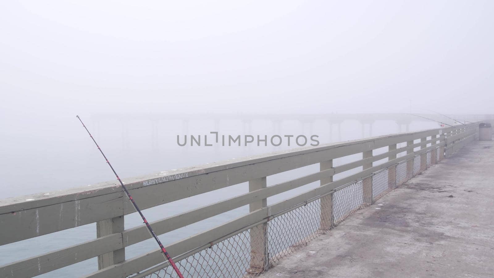 Wooden Ocean Beach pier in fog, misty calm boardwalk in haze, California coast. by DogoraSun
