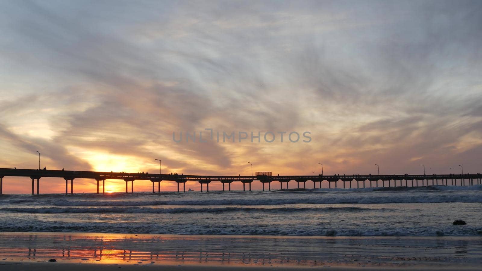 Pier in sea water on beach. Ocean waves, sky at sunset. California coast vibes. by DogoraSun