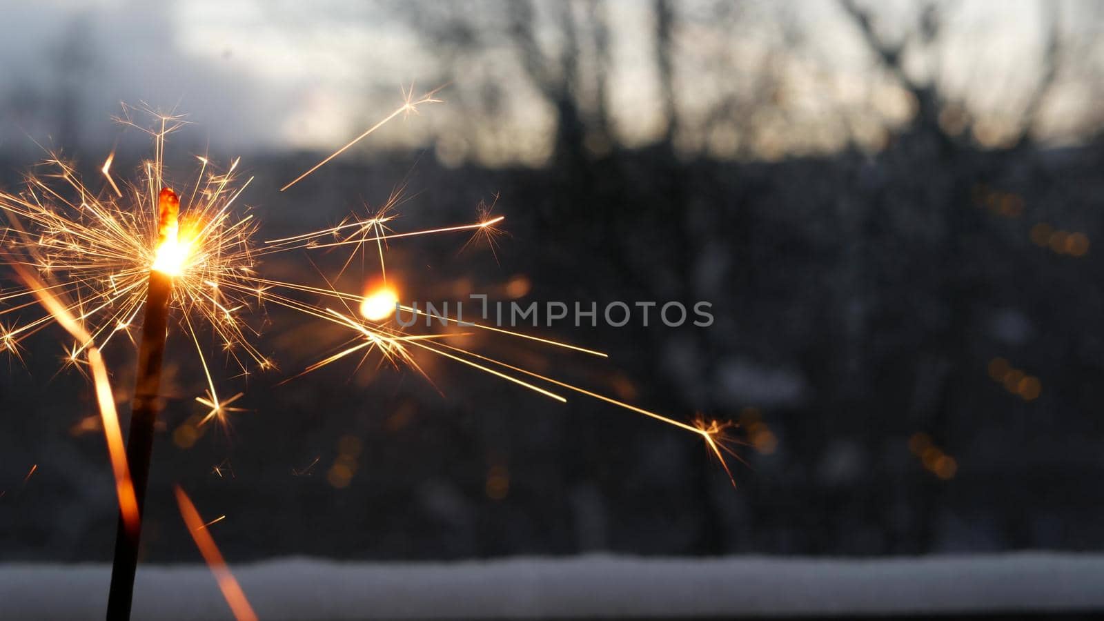Sparkler firework burning on window, New Year or Christmas bengal lights. Winter Xmas holiday celebration magic, sparkles and golden fire stars light glowing in twilight of night.