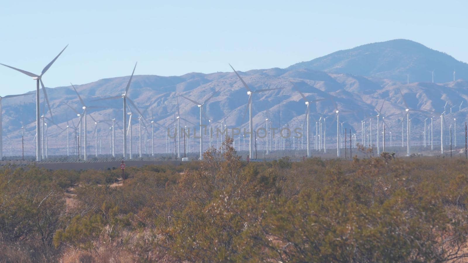 Windmills turbine rotating, wind farm or power plant, alternative green renewable energy generators, industrial field in California, Mojave desert, Tehachapi, USA. Electricity generation on windfarm.