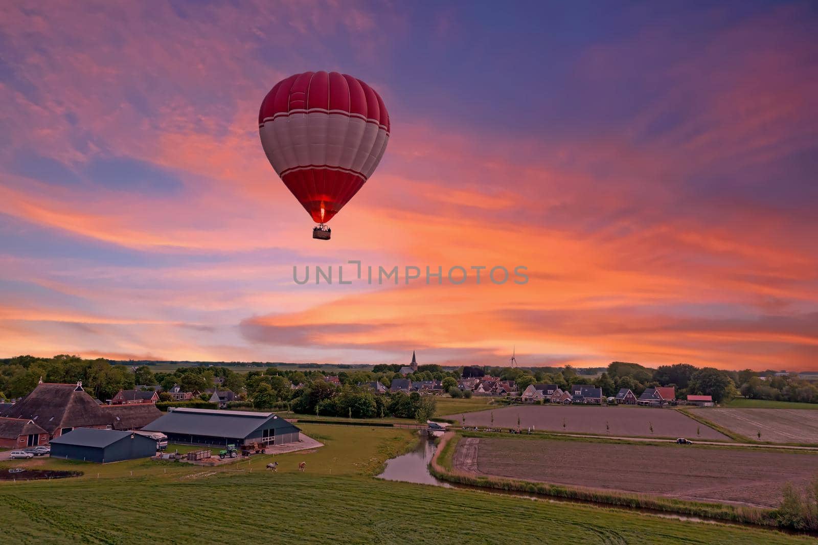 Aerial from a flying hot air balloon in the countryside from the Netherlands at sunset