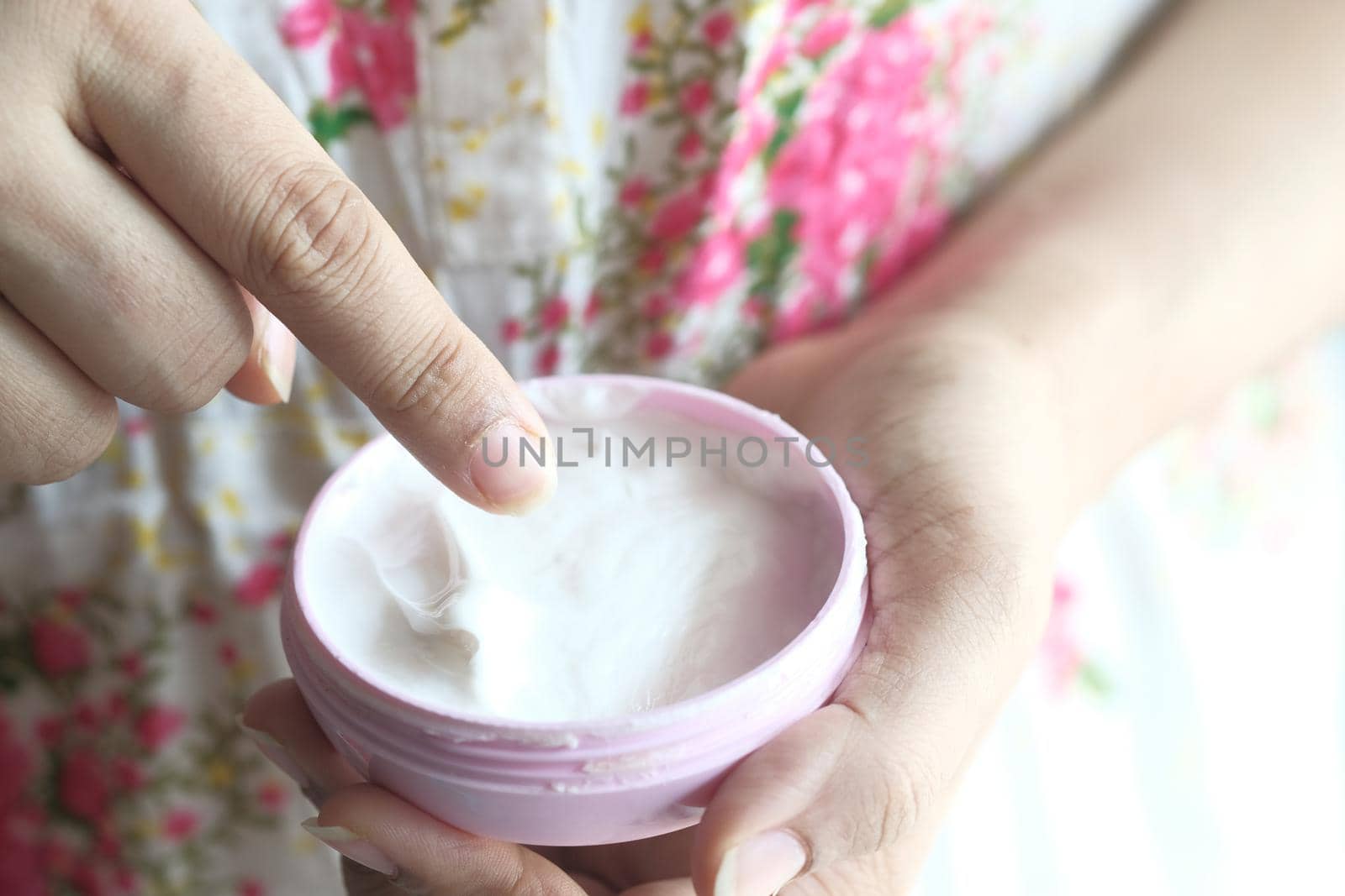 woman applying beauty cream onto skin at home top view.