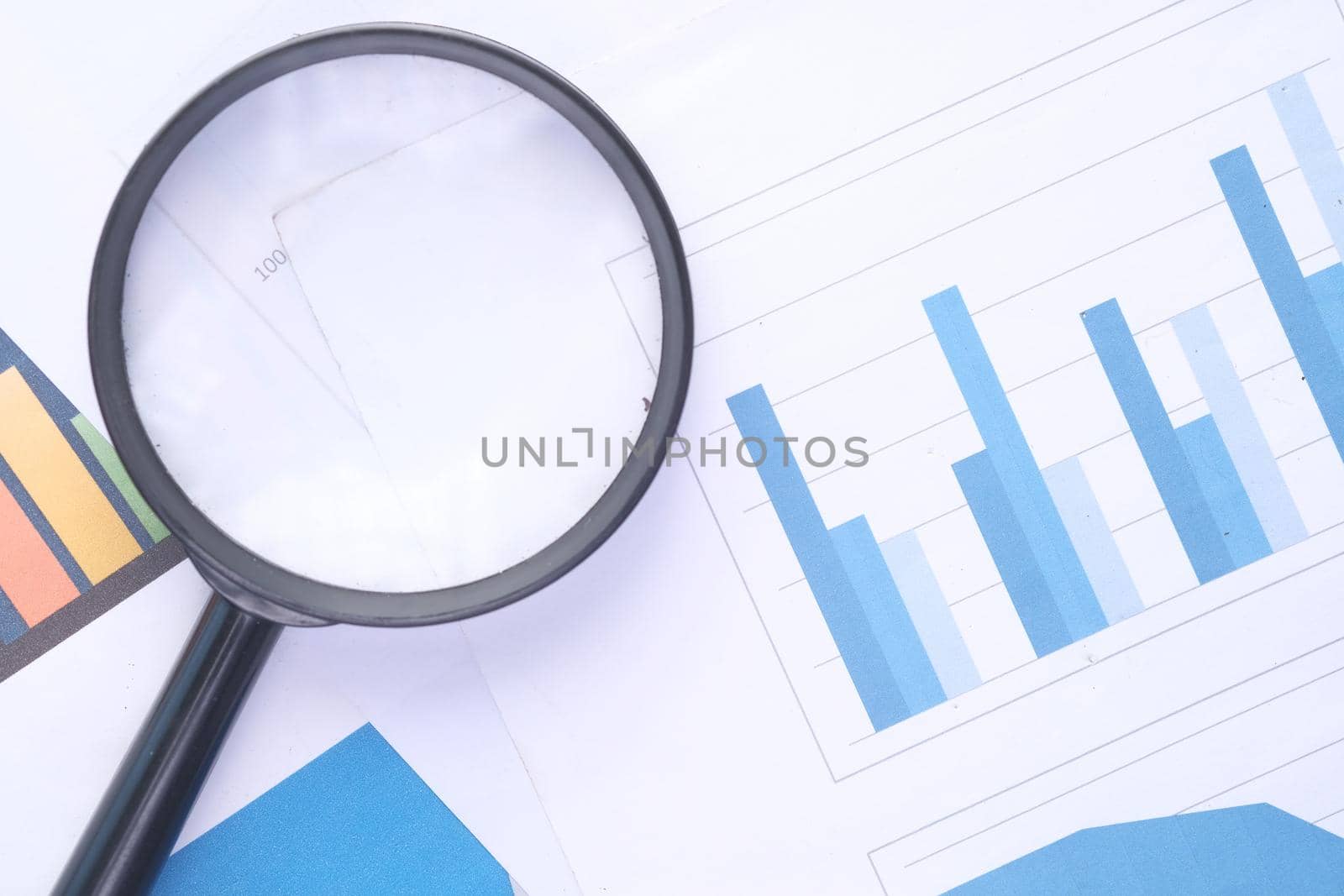 financial graph, magnifying glass on table .