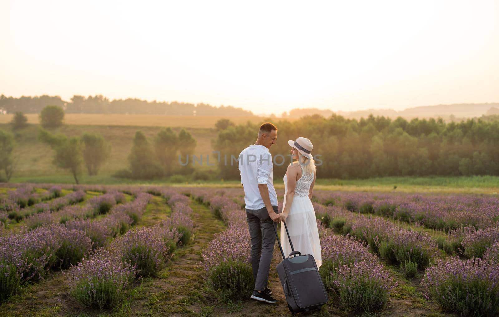 man and woman with suitcase in lavender field.
