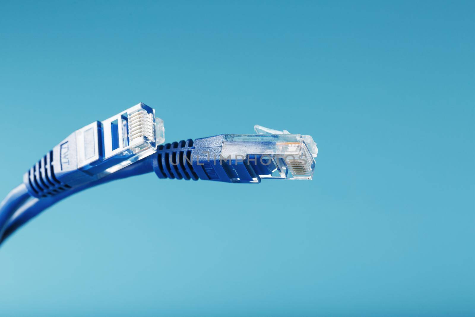 Two Ethernet Cable Connectors Patch cord cord close-up isolated on a blue background with free space by AlexGrec