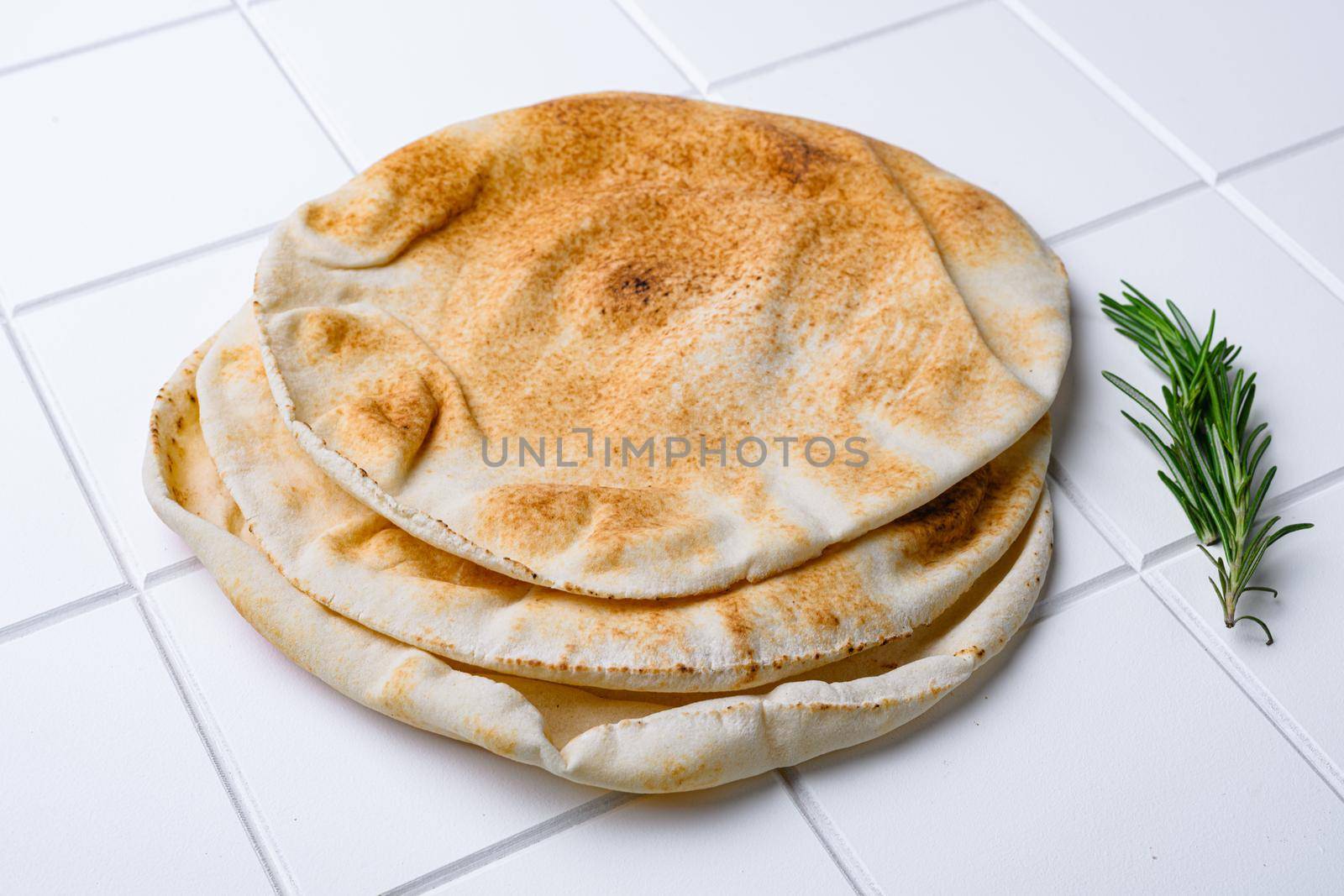 Freshly baked pita bread set, on white ceramic squared tile table background by Ilianesolenyi