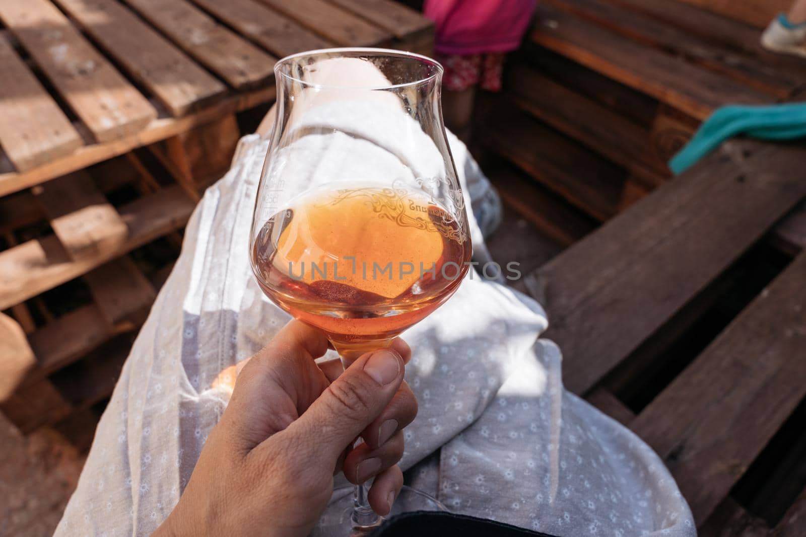 FEMALE hand holding a glass of red drink. Summer, outside