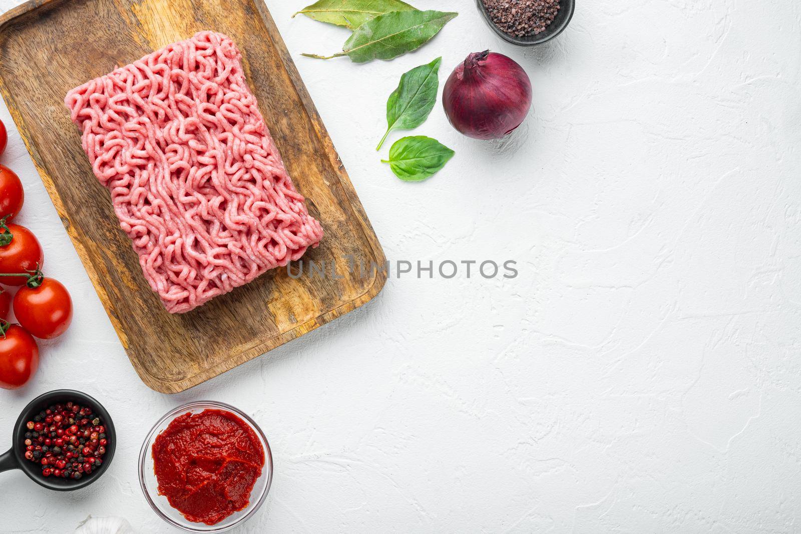 Classic italian bolognese sauce ingredients, ground meat tomatoe and herbs set, on wooden tray, on white stone background, top view, flat lay, with copy space for text