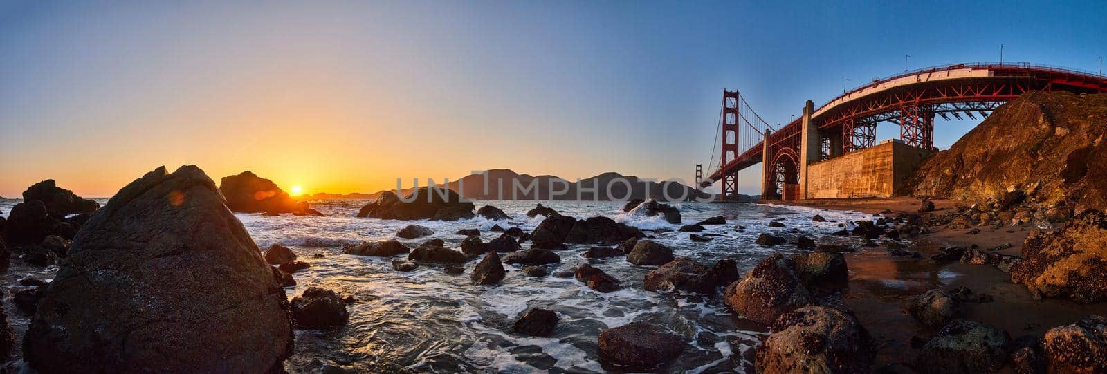 Image of Stunning panorama of Golden Gate Bridge on ocean coast with rocks and sunset