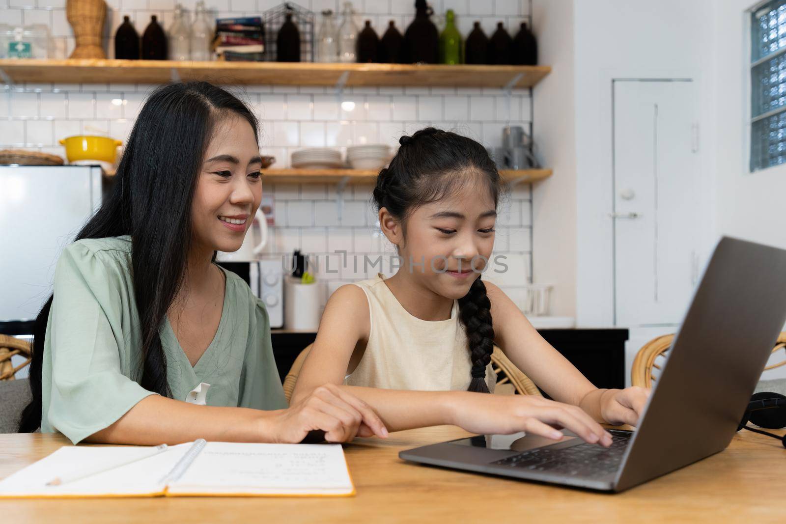 Family and home school concept. Asian mother teach her daughter using application on laptop at home