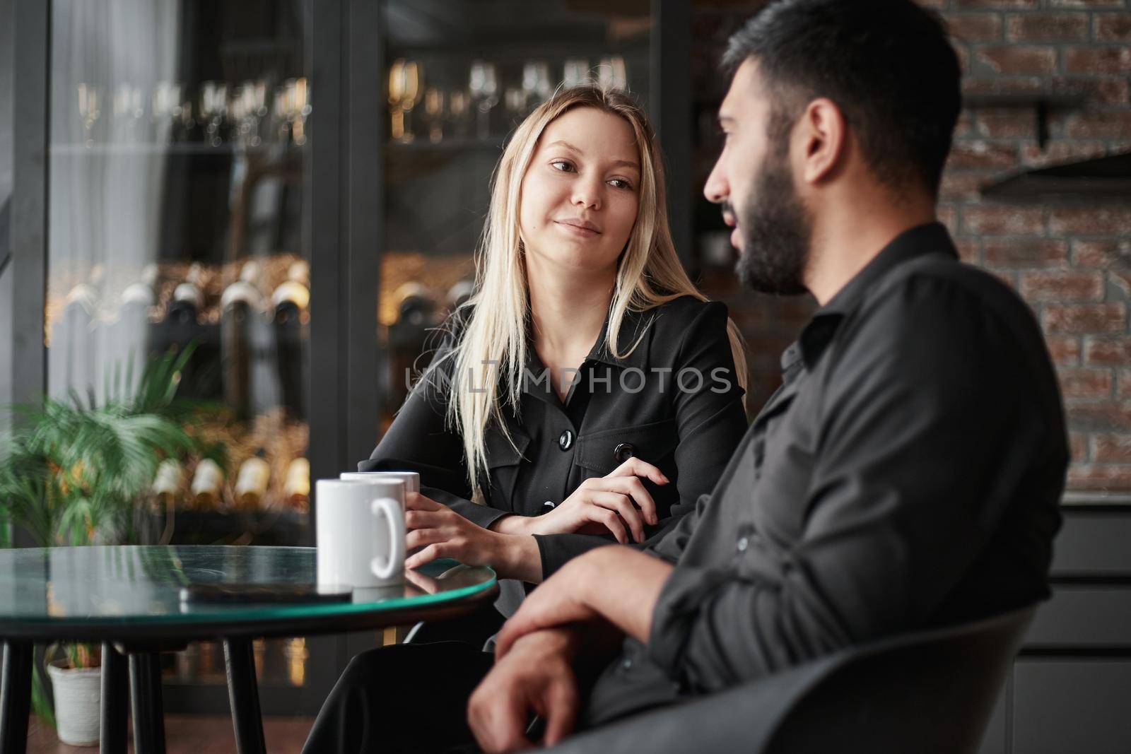 businessman and businesswoman talking sitting at a table in a cafe. by SmartPhotoLab