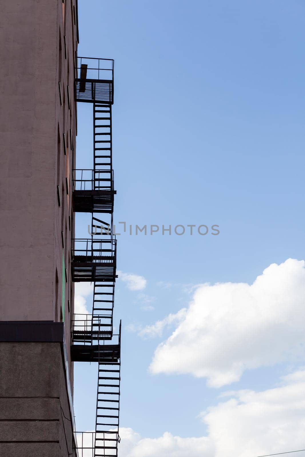 Silhouette of a fire escape on a high-rise building against a blue sky by AnatoliiFoto