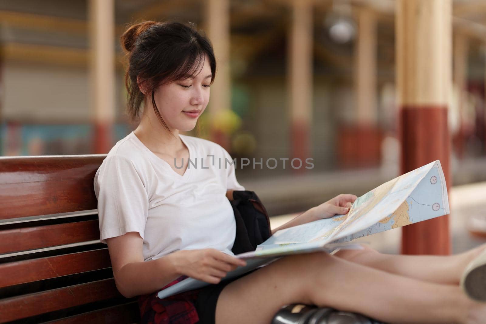 Pretty Young traveler woman looking on maps planning trip at train station. Summer and travel lifestyle concept