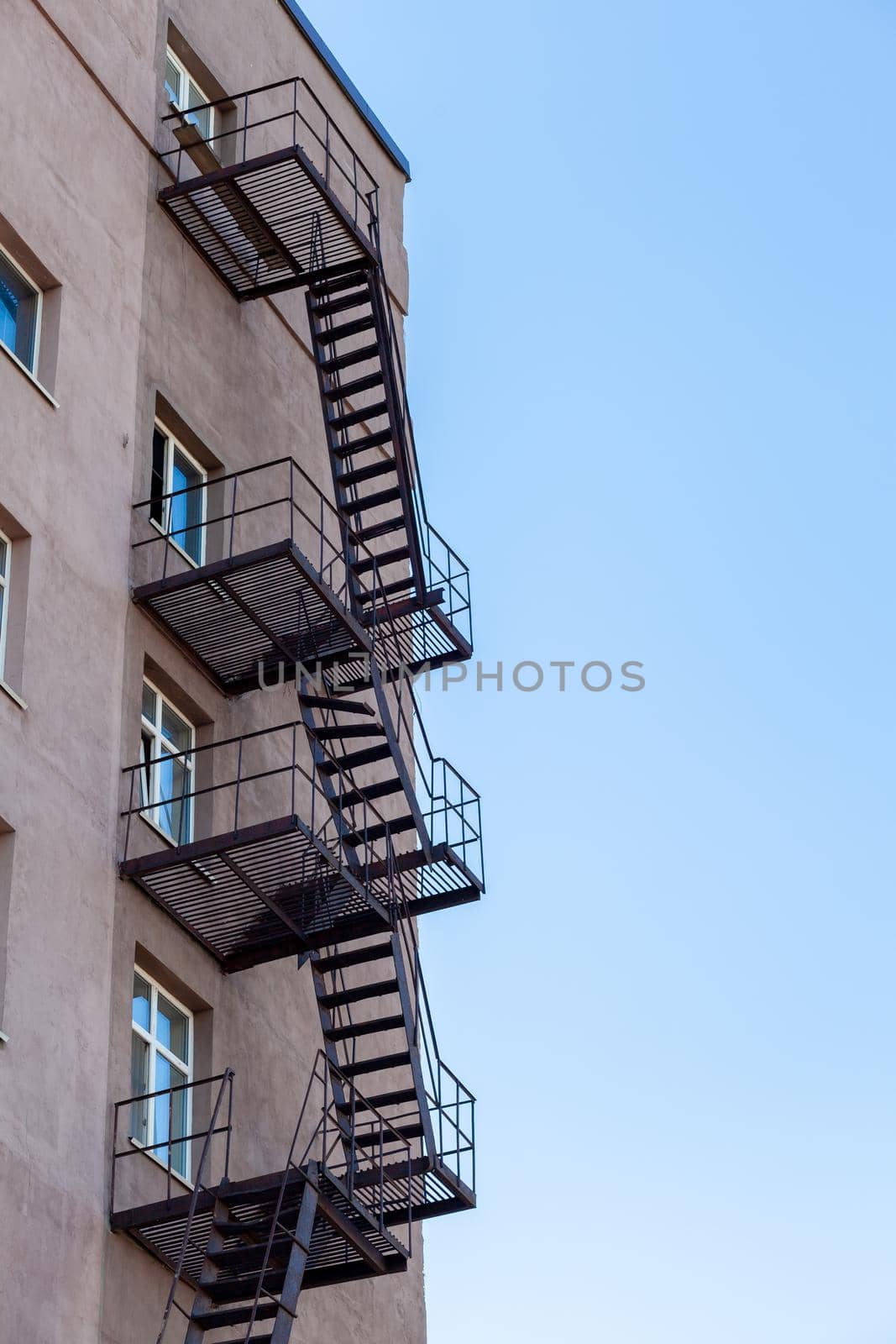 Silhouette of a fire escape on a high-rise building against a blue sky by AnatoliiFoto