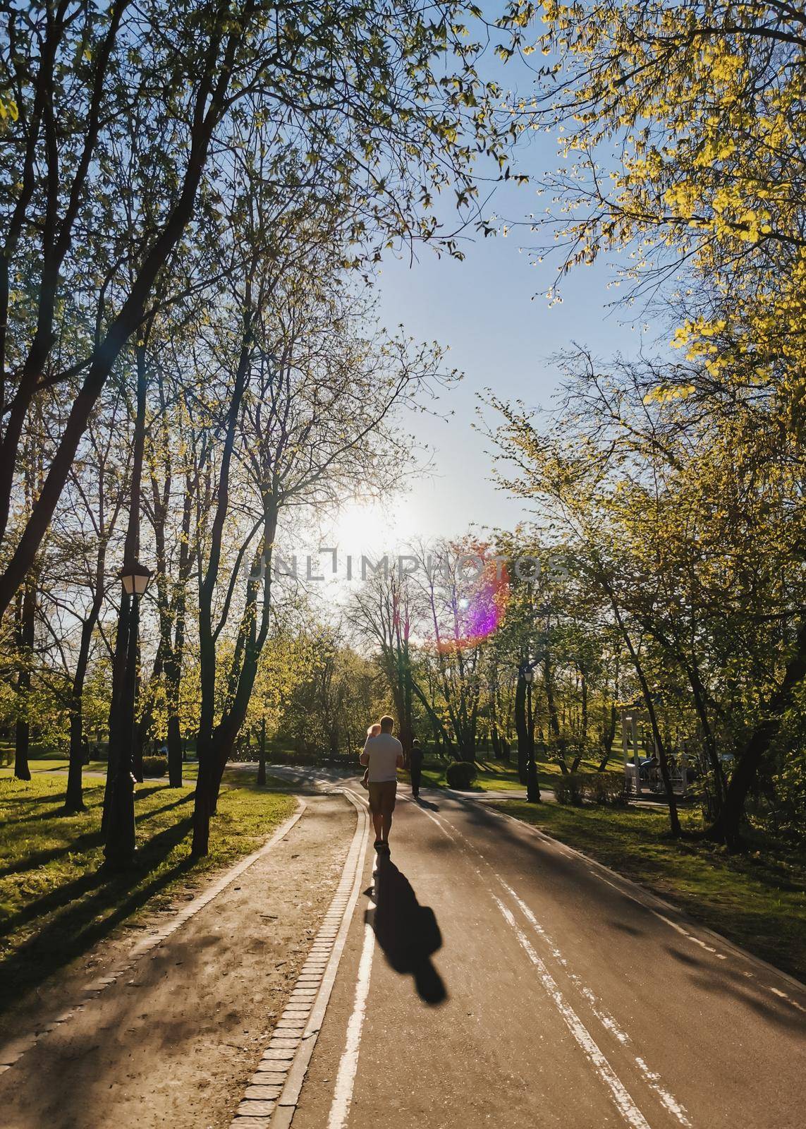 silhouettes father carry child at sunset in summer. Happy family spending time together outside in nature by paralisart