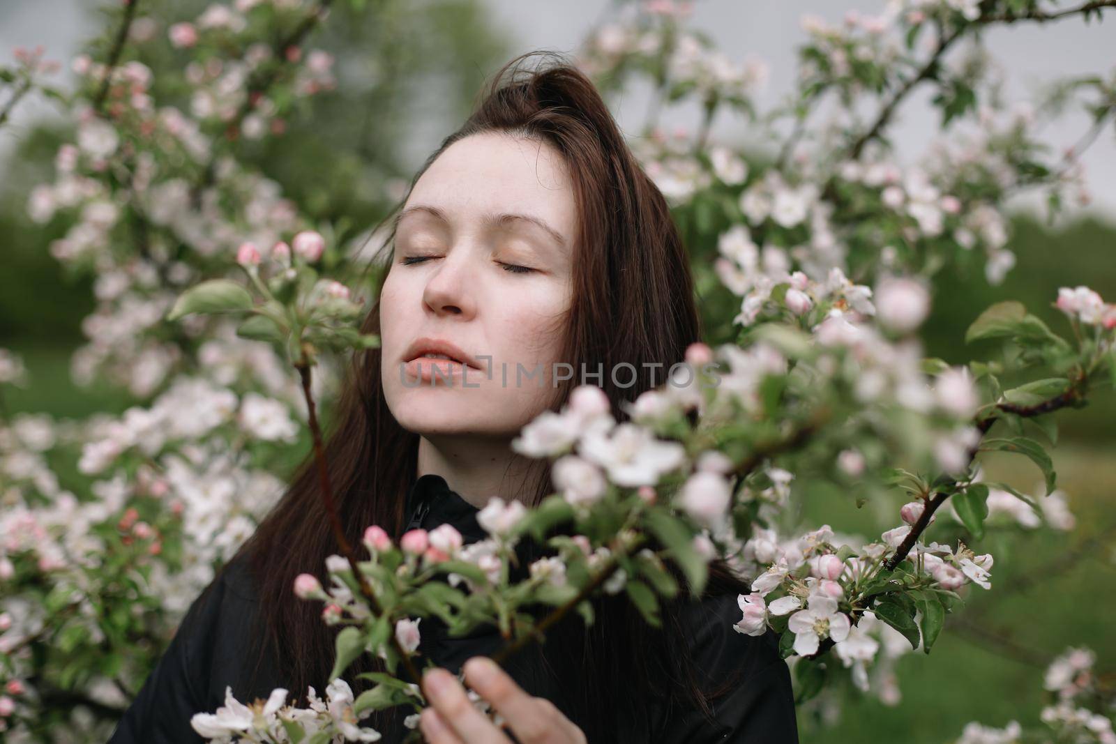 portrait of a beautiful young woman in the spring garden among apple blossom. by paralisart