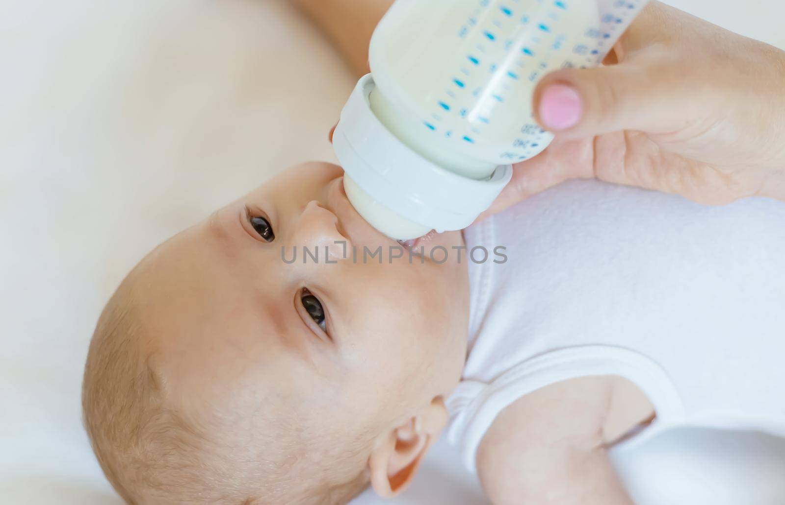 Mom feeds the baby with a bottle. Selective focus. People.