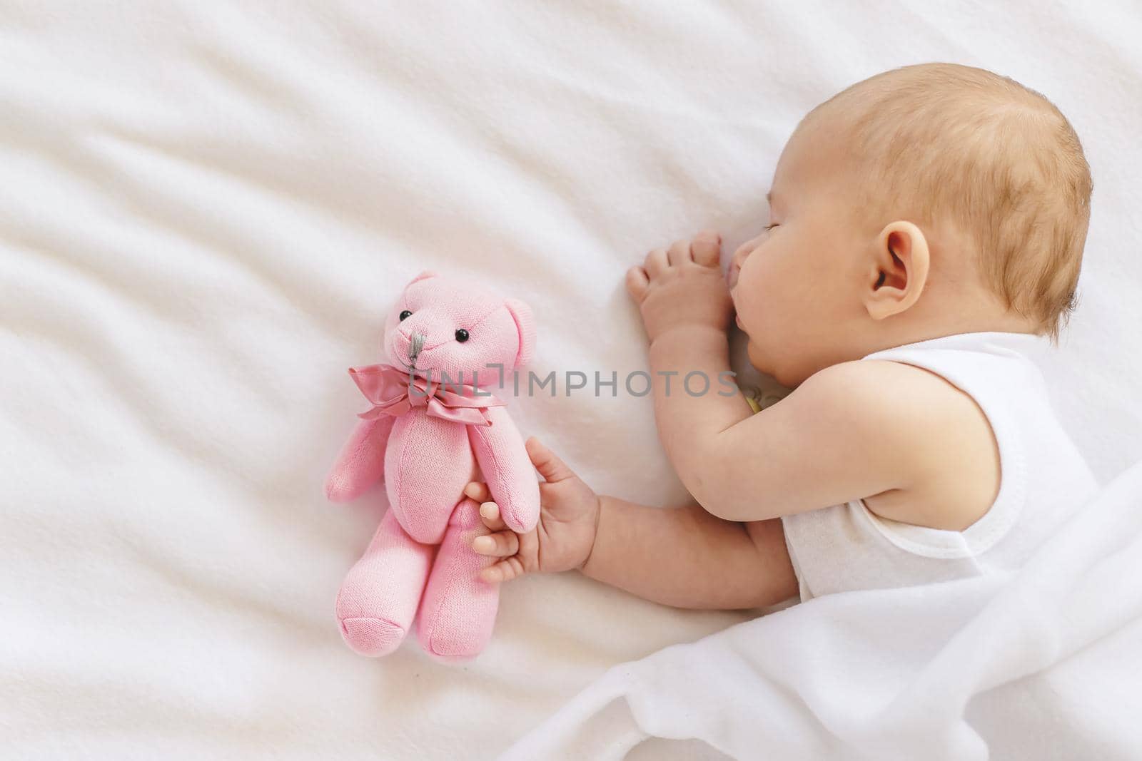 Baby sleeps with a teddy bear on a white background. Selective focus. People.