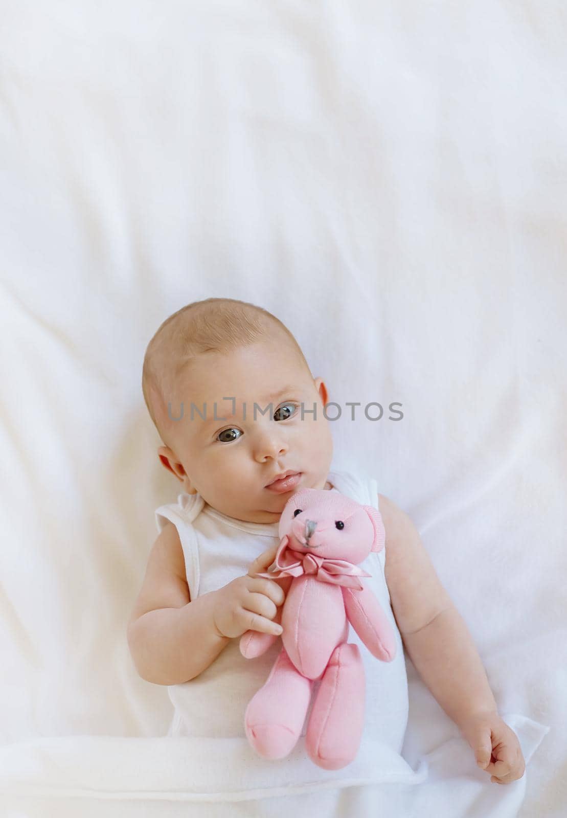 Baby plays with teddy bear against white background. Selective focus. People.