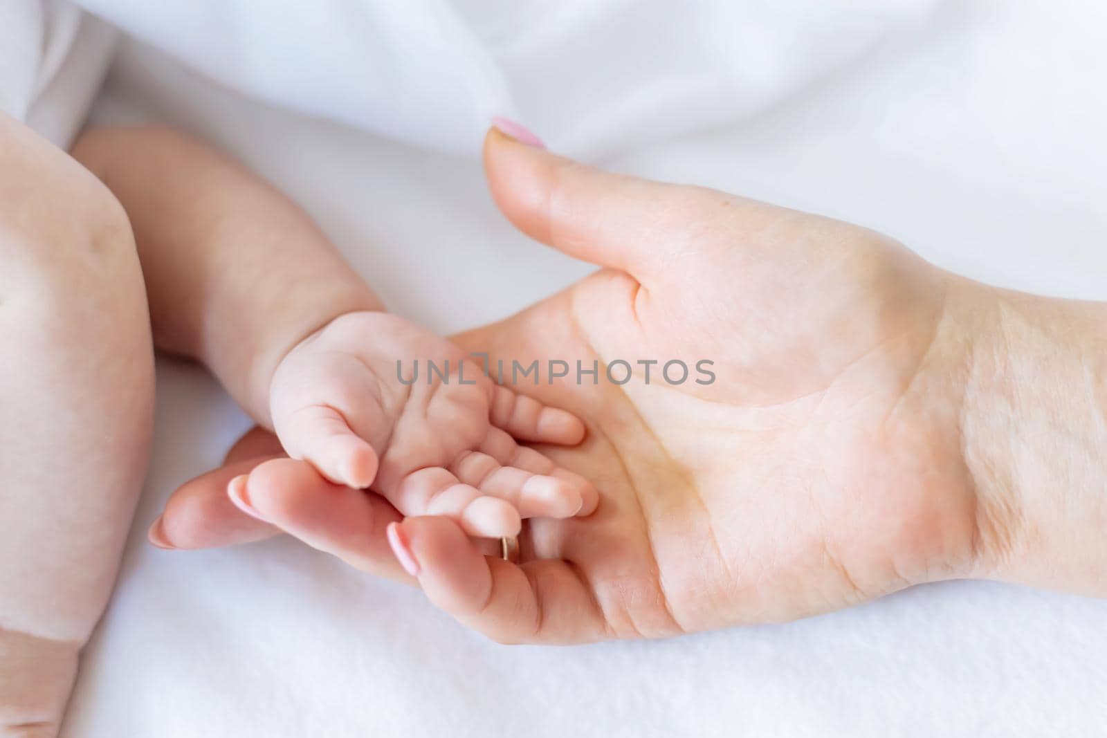 Baby hands with mom's hands against white background. Selective focus. People.